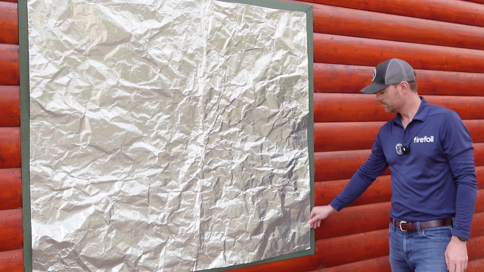 FireFoil technician demonstrating wildfire cover installation on log cabin