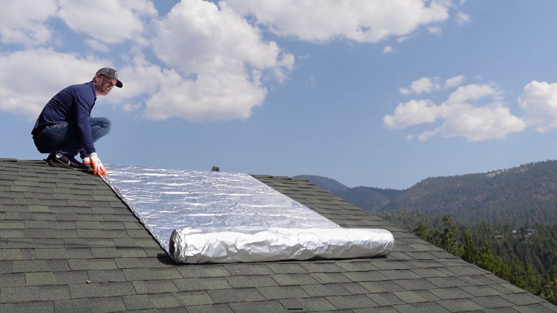 FireFoil technician installing wildfire shield on residential roof with mountain backdrop